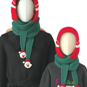 Könnte beinhalten: Zwei gestrickte Kapuzenschals in Rot und Dunkelgrün. Jede Kapuze hat einen roten Rand mit einem weißen Streifen. Die Schals haben lange grüne Enden, die mit kleinen, gehäkelten Weihnachtsmann-Gesichtern mit roten Nasen verziert sind.