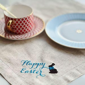 Könnte beinhalten: Eine weiße Keramik-Tasse mit schwarzem Henkel und dem Text "But First, Coffee" in schwarzer, fetter Schrift. Die Tasse steht auf einer weißen Oberfläche. Die Tasse ist etwa 10 cm hoch.