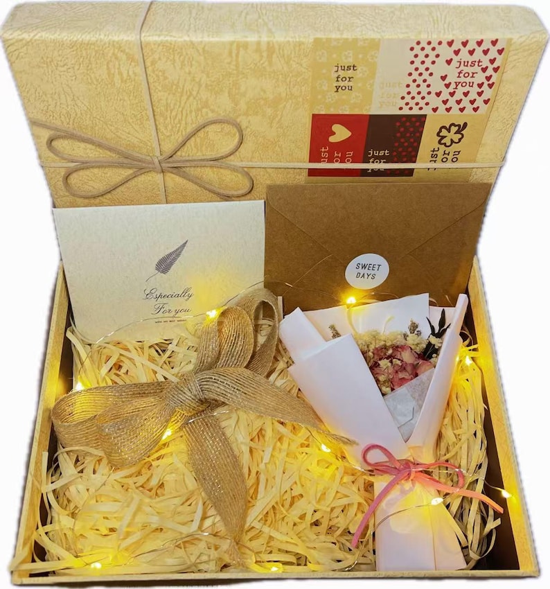 May include: A gift box with a textured beige lid featuring a bow and a label with the text just for you. Inside, the box contains a card with the text Especially For you, a brown envelope with a sticker reading SWEET DAYS, and a small dried flower bouquet.