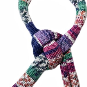 May include: A colorful knitted scarf with a knotted design. The scarf features a mix of colors including blue, purple, green, pink, and white. The scarf is made of a soft, textured material.