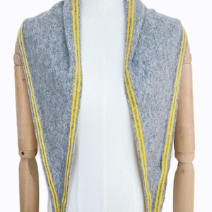 May include: A triangular scarf in heather gray knit fabric featuring two bright yellow stripes running parallel along each of the three edges. The scarf is draped over a mannequin, displaying a textured surface and pointed ends.