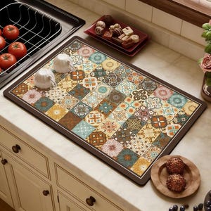 Könnte beinhalten: Eine rechteckige Küchenmatte mit braunem Rand und einem farbenfrohen Patchwork-Design. Die Matte zeigt Quadrate mit floralen und geometrischen Mustern in Braun-, Blau-, Orange- und Gelbtönen. Zwei weiße Teetassen liegen auf der Matte.