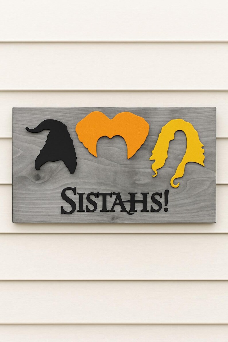 Puede incluir: Letrero de madera con fondo gris que presenta siluetas negras de un sombrero de bruja, cabello naranja y cabello amarillo. La palabra "SISTAH'S!" est&aacute; escrita en letras negras debajo de las siluetas. El letrero est&aacute; montado sobre un revestimiento blanco.