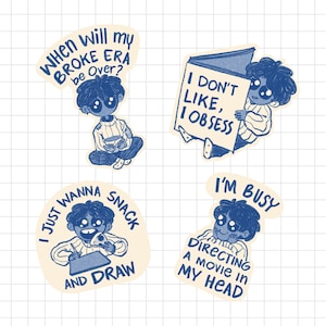May include: Four stickers with blue illustrations on a cream background. Each sticker features a cartoon figure with different phrases: "When will my BROKE ERA be Over?", "I DON'T LIKE, I OBSESS", "I JUST WANNA SNACK AND DRAW", and "I'M BUSY DIRECTING A MOVIE IN MY HEAD".