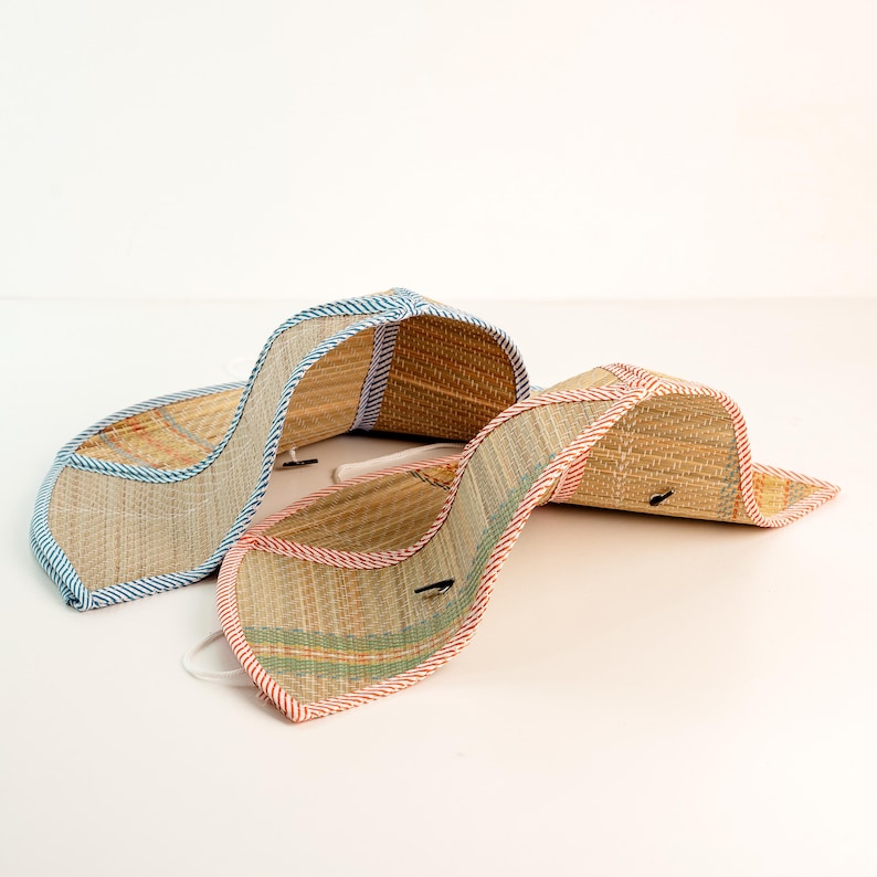 Pair of handmade foldable straw hats, one with blue trim and one with red. Perfect for couples, families, or friends looking for coordinated summer accessories.