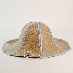 Handwoven straw hat with blue trim, designed for sun protection and comfort. Its lightweight structure makes it perfect for outdoor use, while the traditional weaving pattern reflects craftsmanship and durability.