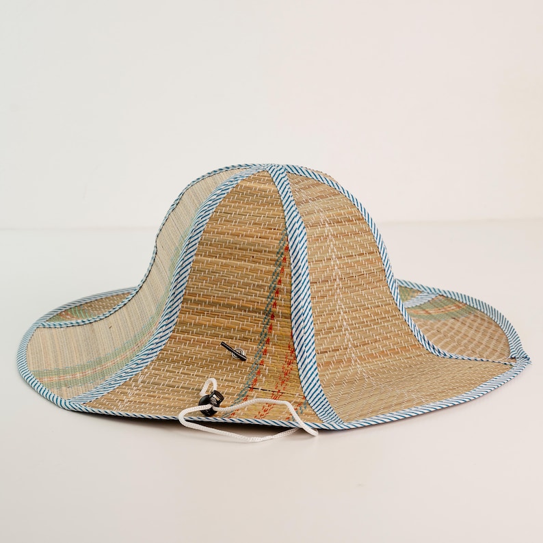 Handwoven straw hat with blue trim, designed for sun protection and comfort. Its lightweight structure makes it perfect for outdoor use, while the traditional weaving pattern reflects craftsmanship and durability.