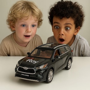 May include: A black toy SUV with the name "Roy" on the hood and "Highlander" on the front. Two children with surprised expressions are looking at the toy car. The car has a sunroof and tan interior.