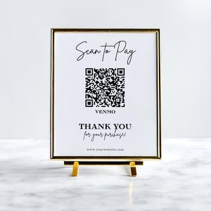 Puede incluir: Un letrero enmarcado con borde y soporte dorados. El letrero dice "Scan to Pay" encima de un código QR, con "Venmo" debajo. También se muestra el texto "THANK YOU for your purchase!" y una dirección web.