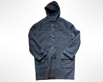 May include: A charcoal gray wool-blend duffle coat featuring a hood, long sleeves with buttoned cuffs, and four wooden toggle closures. The coat includes two large front patch pockets with flaps and a dark plaid lining visible inside the hood.