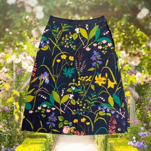 May include: A navy blue skirt with a vibrant floral pattern featuring yellow, blue, and pink flowers, along with green leaves and stems. The skirt has a straight cut and falls to the mid-calf.