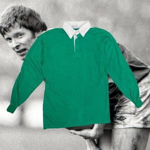 May include: A green rugby shirt with long sleeves, a white collar, and a three-button placket. The shirt is made of a soft material. The background is a black and white image of a person.