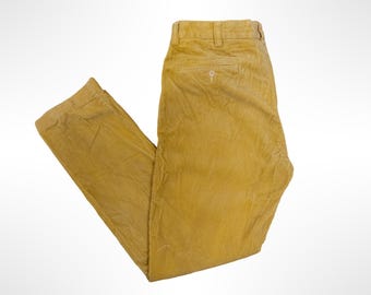 May include: Mustard yellow corduroy trousers featuring a classic straight-leg cut, a waistband with belt loops, and a single rear pocket with a button closure. The fabric has a distinct vertical ribbed texture throughout the garment.