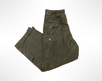Puede incluir: Pantalones cargo de color verde oliva con diseño de cintura alta y cierres de botón, un bolsillo cargo lateral con solapa abotonada y un bolsillo más pequeño con botón en la parte superior del muslo. Tienen corte recto y dobladillos.