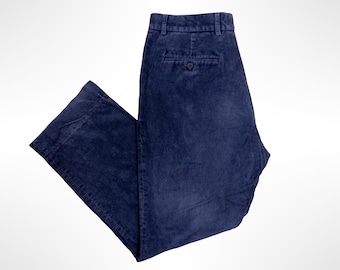 May include: A pair of dark navy blue corduroy trousers featuring a textured ribbed fabric, a waistband with belt loops, and a single rear pocket with a button closure. The pants are shown from the back, displaying the straight leg cut.