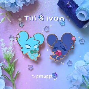 May include: Two enamel pins featuring mouse-like characters in light blue and navy blue, each with gold accents. The light blue mouse has a stern expression, while the navy blue mouse appears serene. The pins are set against a pastel background with the text "Till & Ivan".