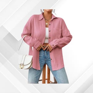 Puede incluir: Una camisa rosa claro con botones, mangas largas y un bolsillo en el pecho. La camisa se combina con vaqueros azul claro y un bolso blanco con hebilla dorada. El conjunto es casual y elegante.