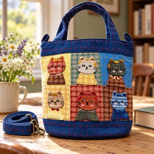 Bolsa estilo saco azul-marinho com patchwork de gato, detalhes bordados à mão e alça transversal removível.