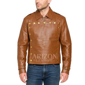 May include: A brown leather jacket with a zip-up front and a collared neckline. The jacket features gold-colored buttons and the text "ARIZON LEATHER". The model is wearing blue jeans.