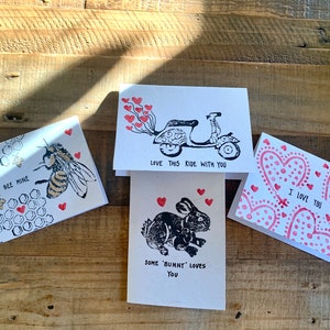 May include: A collection of four handmade greeting cards with romantic themes. One card features a bee with the text "Bee Mine", another a scooter with "Love this ride with you", a third a bunny with "Some 'Bunny' loves you", and the last one with "I Love You".