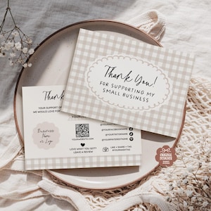 Puede incluir: Dos tarjetas de agradecimiento a cuadros beige y blancos con el texto "Thank You! For supporting my small business" en un óvalo decorativo. Las tarjetas están sobre un plato con una bolsa tejida y ramitas de flores blancas.