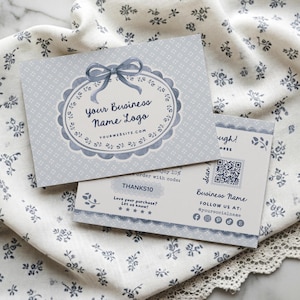 May include: Two light blue business cards with a floral design and the text "Your Business Name Logo" and "THANKS10". The cards are on a white floral patterned cloth.