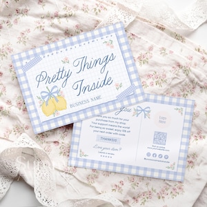 Könnte beinhalten: Zwei hellblau-weiß karierte Karten mit dem Text "Pretty Things Inside" und einer Zitronenillustration. Die Karten sind mit floralen Akzenten und einer Schleife verziert. Die Karten liegen auf einem floralen Stoff.