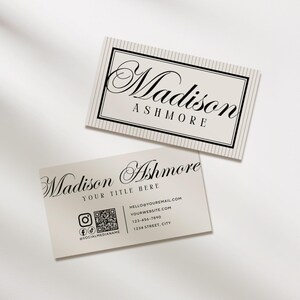 Pu&ograve; includere: Due biglietti da visita con il nome "Madison Ashmore" in elegante scrittura. Un biglietto ha un bordo a righe e l'altro include informazioni di contatto, icone di social media e un codice QR. I biglietti sono beige chiaro con testo nero.