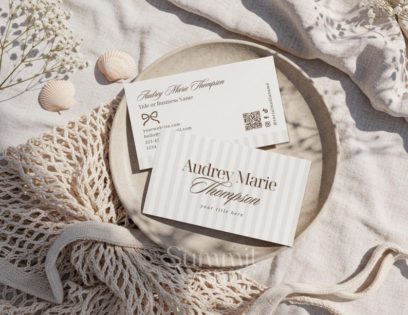 Puede incluir: Dos tarjetas de visita con el nombre "Audrey Marie Thompson" se muestran en un plato. Una tarjeta tiene rayas verticales y la otra un lazo. Las tarjetas incluyen informaci&oacute;n de contacto y redes sociales.