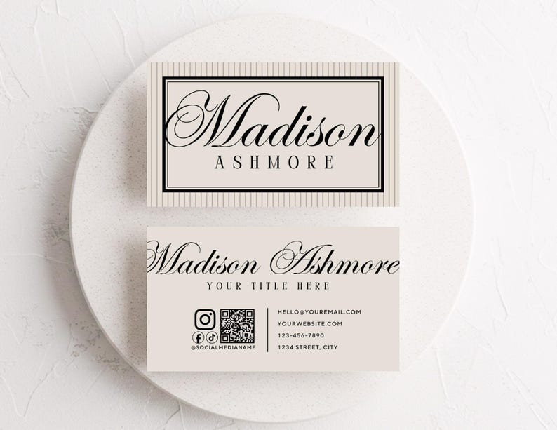 Pu&ograve; includere: Due biglietti da visita con il nome "Madison Ashmore" in elegante scrittura. La carta superiore ha uno sfondo a righe e quella inferiore include icone di social media, un codice QR e informazioni di contatto. Le carte sono beige chiaro.