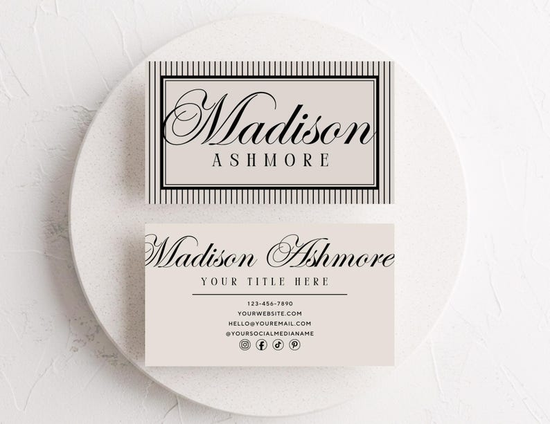 May include: Two business cards with the name "Madison Ashmore" in elegant script. One card features a striped border and the name, while the other includes contact information and social media icons. The cards are light beige.