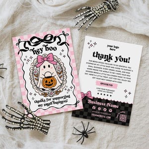 May include: Two rectangular cards with Halloween themes. The left card features a pink checkered background, a ghost with a pink bow holding a pumpkin, and the text 'hey boo'. The right card is white and black with 'thank you!' and 'SPOOKY10'.
