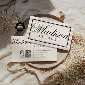 Pu&ograve; includere: Due biglietti da visita con il nome "Madison Ashmore" in elegante scrittura. Uno &egrave; sopra l'altro, con un bordo nero e uno sfondo a righe. Il biglietto inferiore include icone di social media e informazioni di contatto.