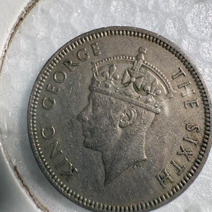 May include: A silver coin featuring a profile of King George VI wearing a crown, with the inscriptions "KING GEORGE" and "THE SIXTH" around the edge. The coin is set against a white background.