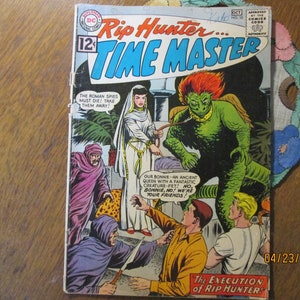 May include: A comic book cover featuring a green monster with red hair and a woman in a white robe. The text on the cover reads "Rip Hunter... Time Master" and "The Execution of Rip Hunter!"