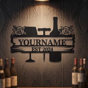 Könnte beinhalten: Schwarze Metall-Wandkunst mit Wein-Motiv, zeigt ein Weinglas, eine Flasche und einen Korkenzieher. Der Text "YOURNAME EST 2024" ist prominent dargestellt. Rosen schmücken die Oberseite. Weinflaschen sind im Hintergrund zu sehen.