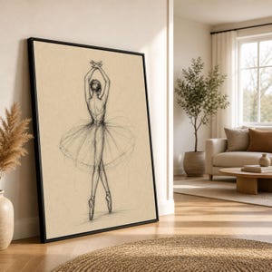 May include: A framed pencil sketch of a ballerina en pointe, arms raised overhead. The artwork features a black frame and is displayed against a neutral background. The ballerina is wearing a tutu. The artwork is displayed in a living room.