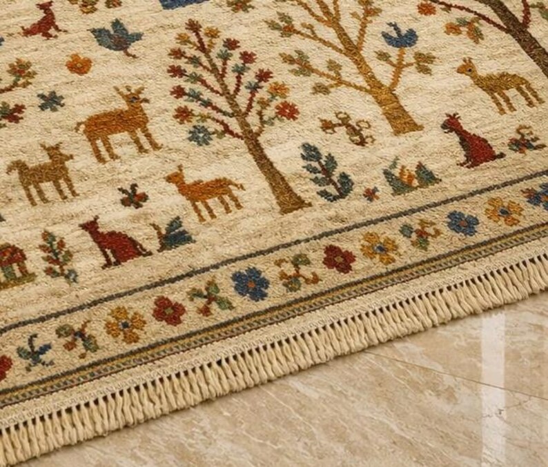 Pu&ograve; includere: Tappeto beige con un motivo ripetuto di alberi, cervi ed elementi floreali nei toni del marrone, rosso, blu e giallo. Il tappeto ha un bordo con frange e un bordo con disegni floreali e geometrici. Lo stile &egrave; rustico e decorativo.