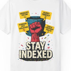 Może przedstawiać: Biała koszulka z grafiką. Czerwona pięść wyłania się z niebieskiego pojemnika, otoczona żółtymi znakami z komunikatami o błędach. Poniżej grafiki znajduje się napis "STAY INDEXED".