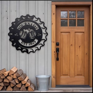 Könnte beinhalten: Ein rundes Wand-Schild aus schwarzem Metall in Form eines Kronkorkens mit einem Ausschnitt-Design von zwei anstoßenden Bierkrügen, dem Text "YOUR NAME" in einem Bogen darüber und dem Text "EST 2025" unter den Krügen in einer klaren Schrift.