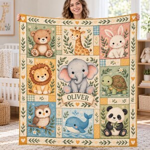 Può includere: Una coperta rettangolare per neonati con una griglia di illustrazioni di un orso, giraffa, coniglio, leone, elefante, tartaruga, gufo, balena e panda. Il grafico centrale dell'elefante include un banner con il nome OLIVER in verde.