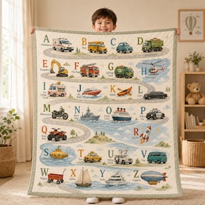 Può includere: Una coperta trapuntata con un design alfabetico dalla A alla Z, in cui ogni lettera è abbinata a un'illustrazione di un veicolo e alla relativa etichetta. Il tessuto chiaro mostra una strada tortuosa e percorsi d'acqua con vari mezzi.