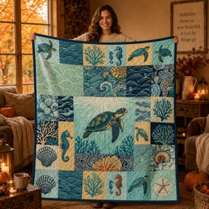 Peut inclure: Un jeté de lit matelassé présentant une tortue de mer centrale entourée de carrés en patchwork de vagues, récifs coralliens, coquillages et hippocampes dans des tons bleu, turquoise et crème avec une bordure bleu foncé et des coutures.