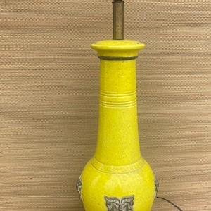 May include: A vintage yellow ceramic table lamp with a brass neck and a dark base. The lamp has a textured surface and decorative elements. The lamp is approximately 24 inches tall.