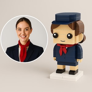 以下が含まれることがあります： ネイビーブルーの制服、赤いスカーフ、帽子を身に着けた客室乗務員のレゴスタイルのフィギュア。フィギュアは白い台座の上に立っています。ネイビーブルーのブレザーと赤いスカーフを着た笑顔の女性が円形のインセットにいます。