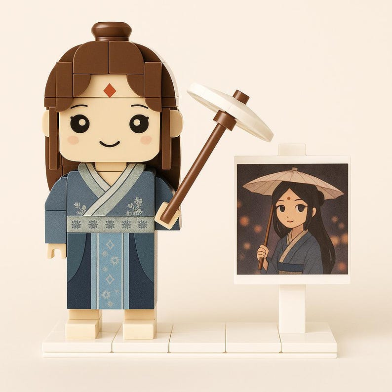 May include: A Lego-style figure of a woman in a blue robe, holding a brown and white parasol. The figure has brown hair and a red gem on her forehead. A small picture of a woman with a parasol is next to the figure.