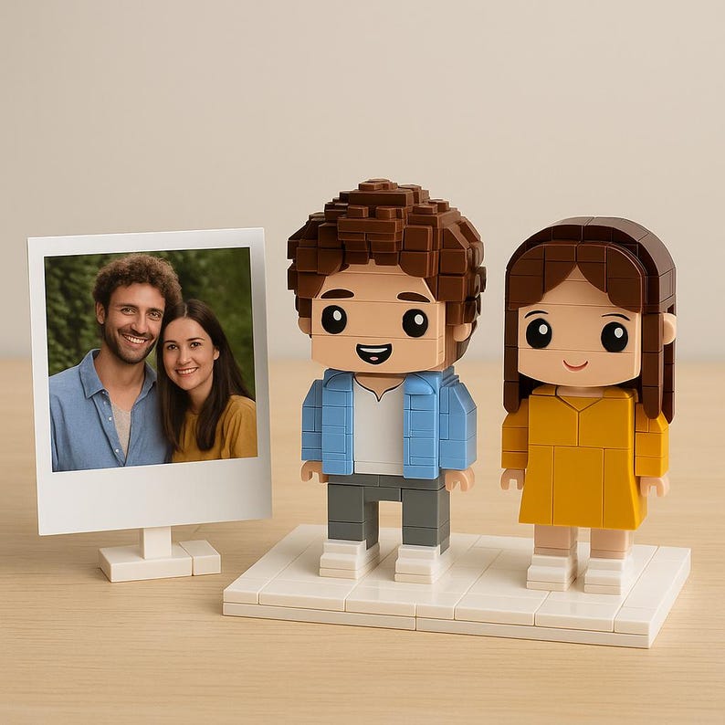 May include: A personalized gift set featuring a framed photo and two Lego-style figurines. The figurines depict a couple, one in a blue jacket and the other in a yellow dress. The photo shows a smiling couple.