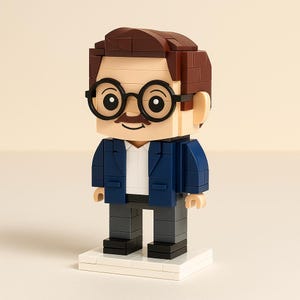 May include: A brick-built figure of a man with brown hair, a mustache, and black-rimmed glasses. He wears a blue blazer over a white shirt, gray pants, and black shoes. The figure stands on a white base.