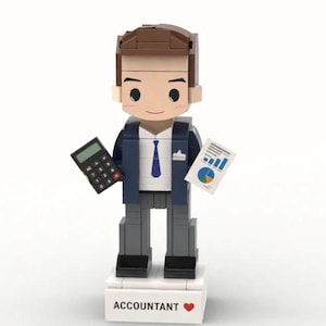 Op de afbeelding: Een Lego-stijl figuur van een accountant, gekleed in een marineblauwe blazer, grijze broek en een blauwe stropdas. Het figuur houdt een rekenmachine en een grafiek met een cirkeldiagram vast. De basis leest "ACCOUNTANT" met een rood hart.
