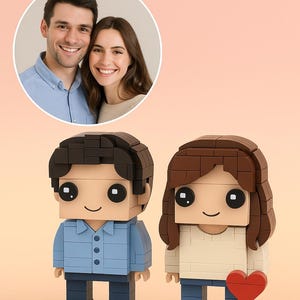 May include: A personalized Lego-style couple figurine with a photo in a circular frame. The male figure wears a blue shirt and the female figure wears a cream-colored top. A red heart is held by the female figure. The figures stand on a white base.
